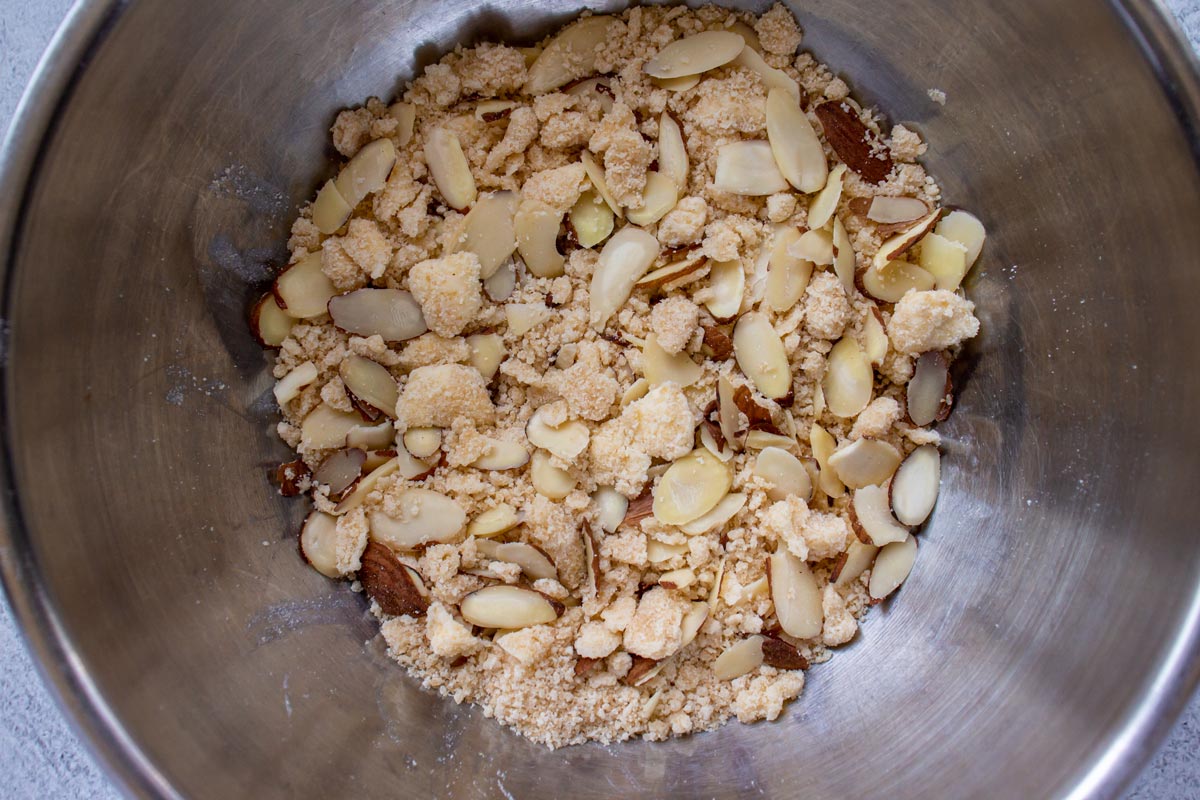 Streusel topping with sliced almonds in a metal mixing bowl.
