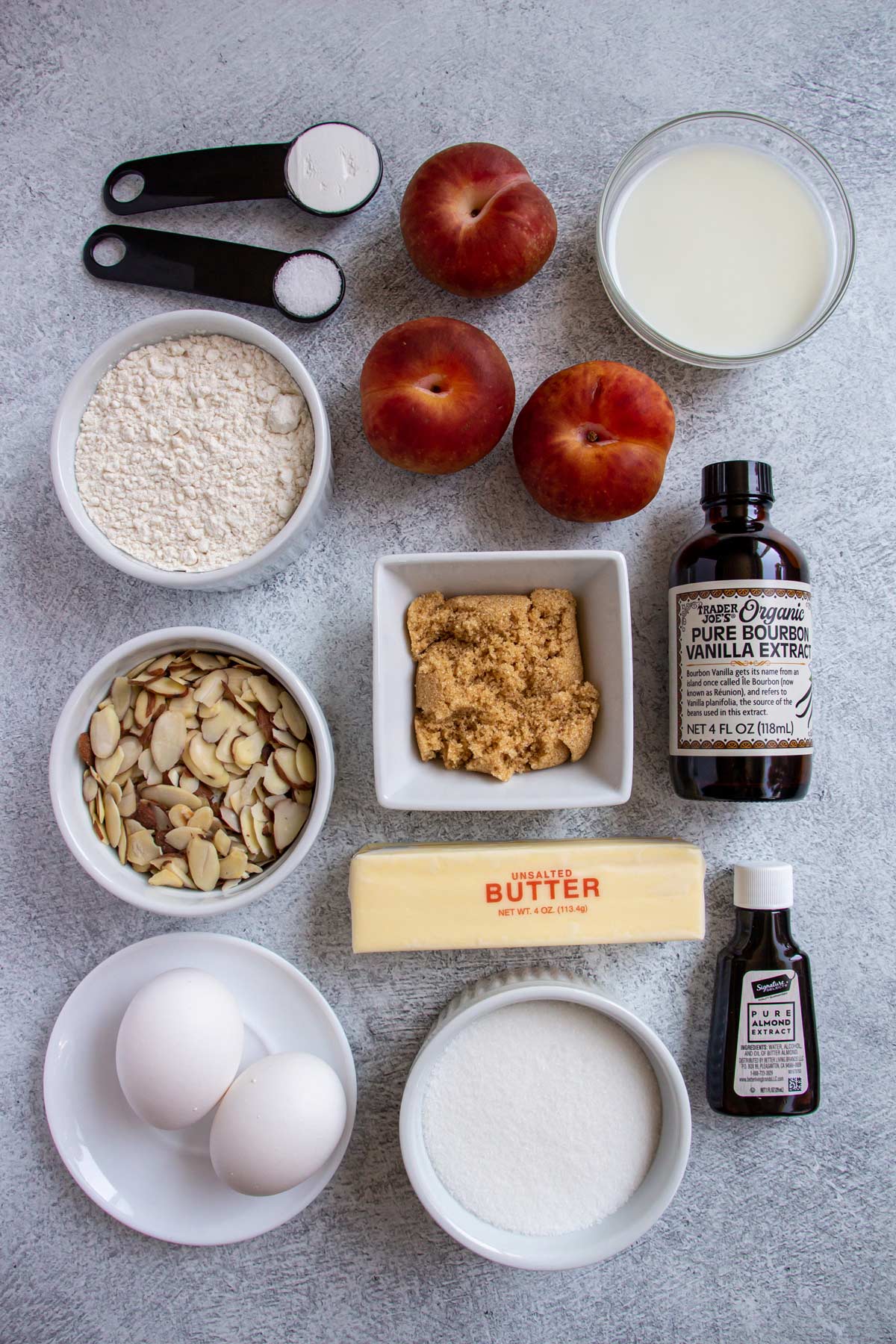 Ingredients for plum almond muffins on a grey background.
