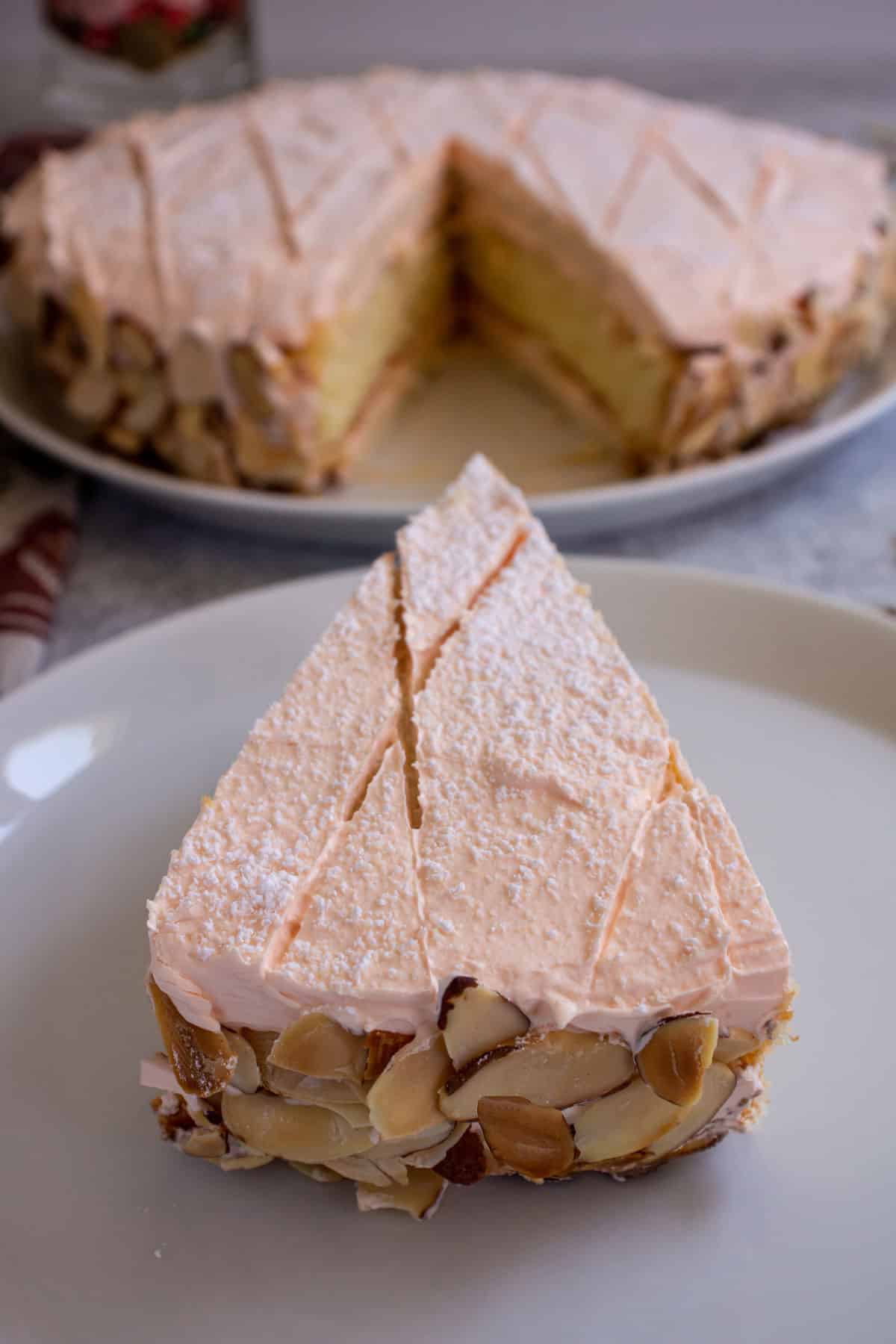 A slice of cake with sliced almonds along the edge served on a white plate.