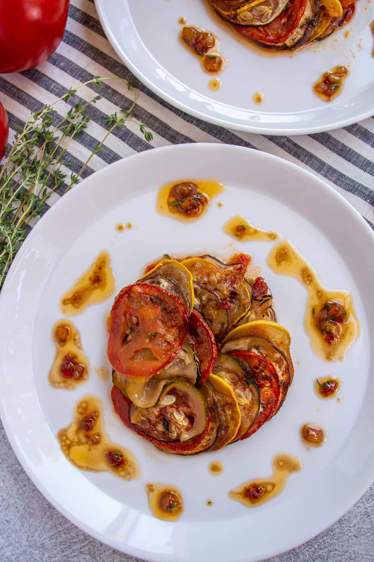 Thomas Keller's ratatouille made with thinly sliced vegetables fanned into a circle on a white plate.