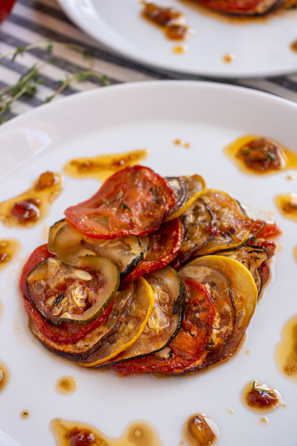 Ratatouille fanned into a circle on a white plate with a drizzle of vinaigrette around it.