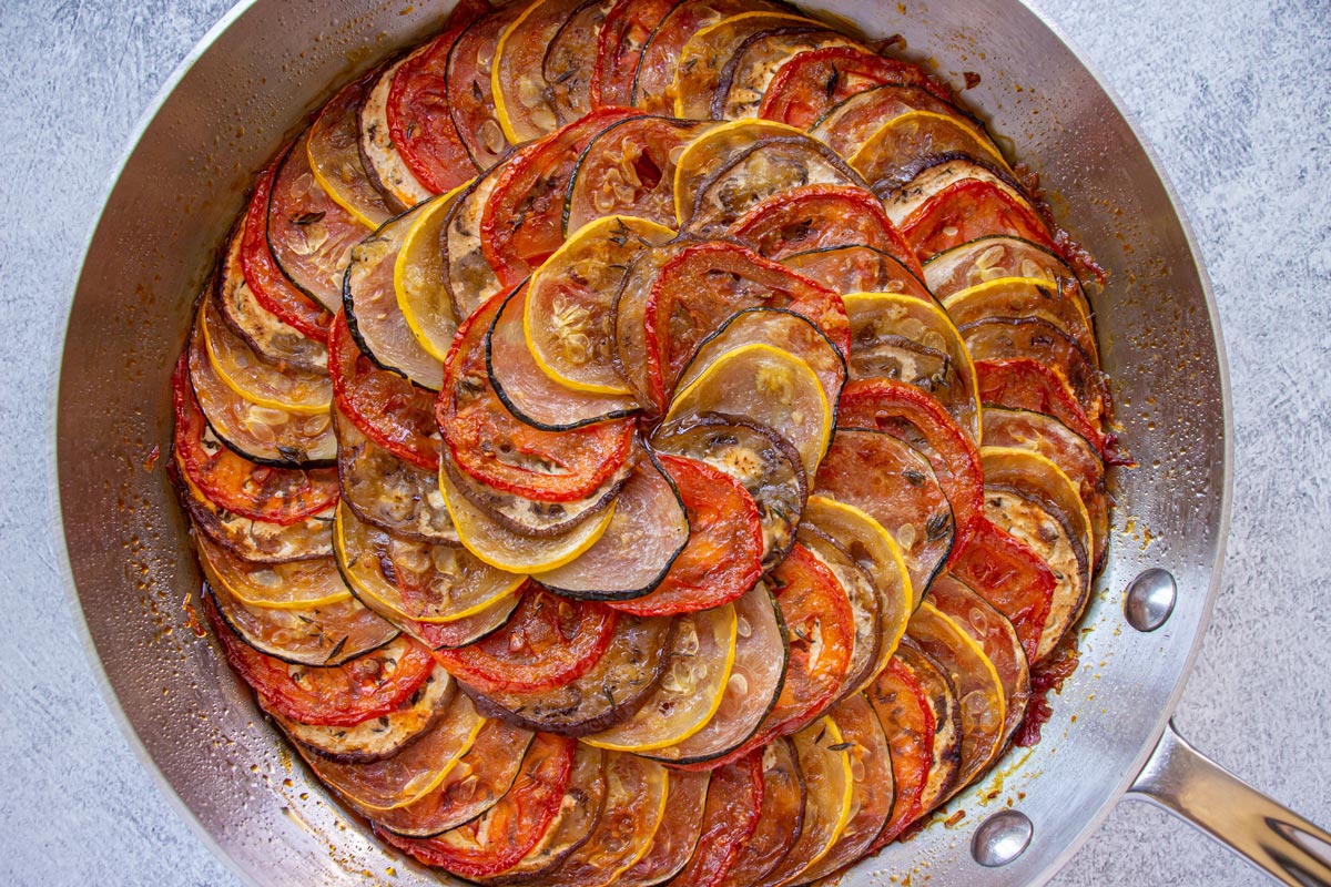 An elegant ratatouille with vegetable slices arranged in a spiral pattern in a skillet.