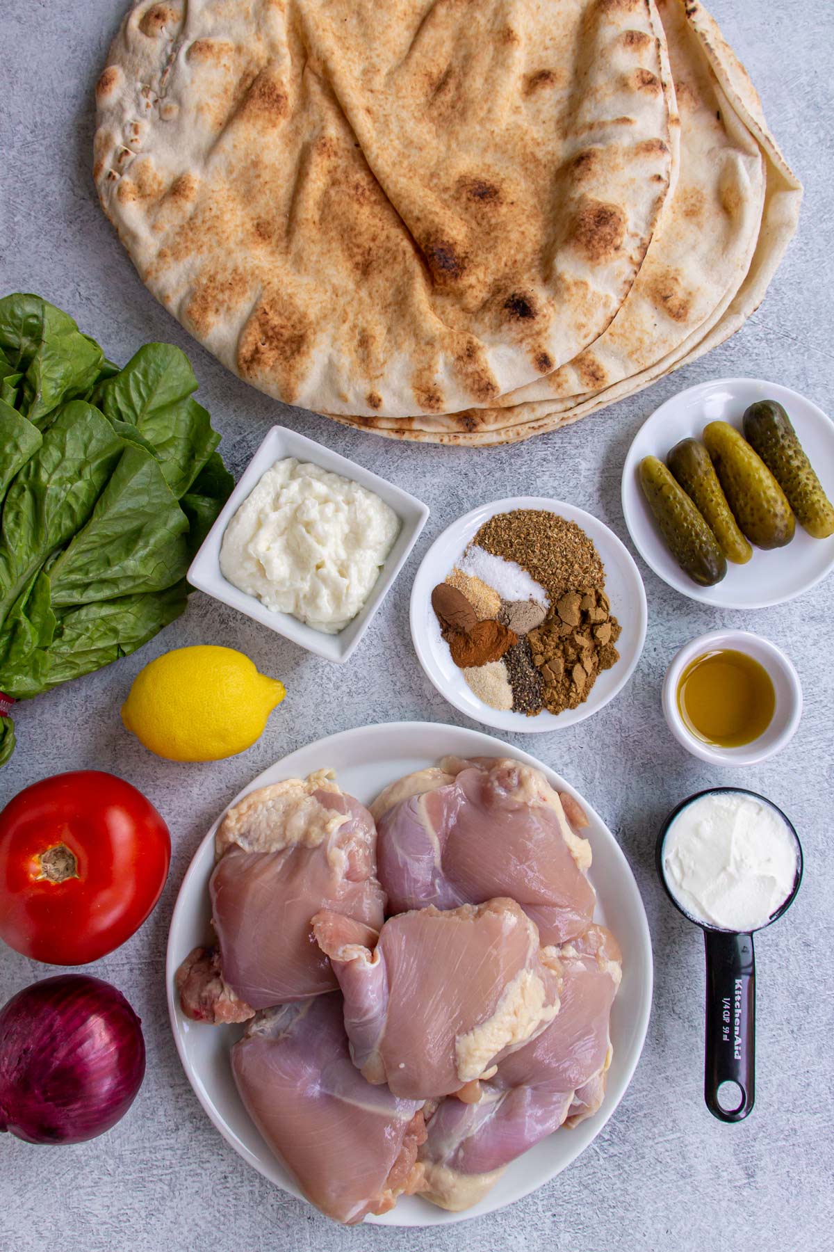 Ingredients for chicken shawarma wraps on a light grey background.