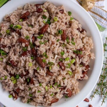 Jamaican rice and peas in a wide white bowl garnished with sliced scallions.