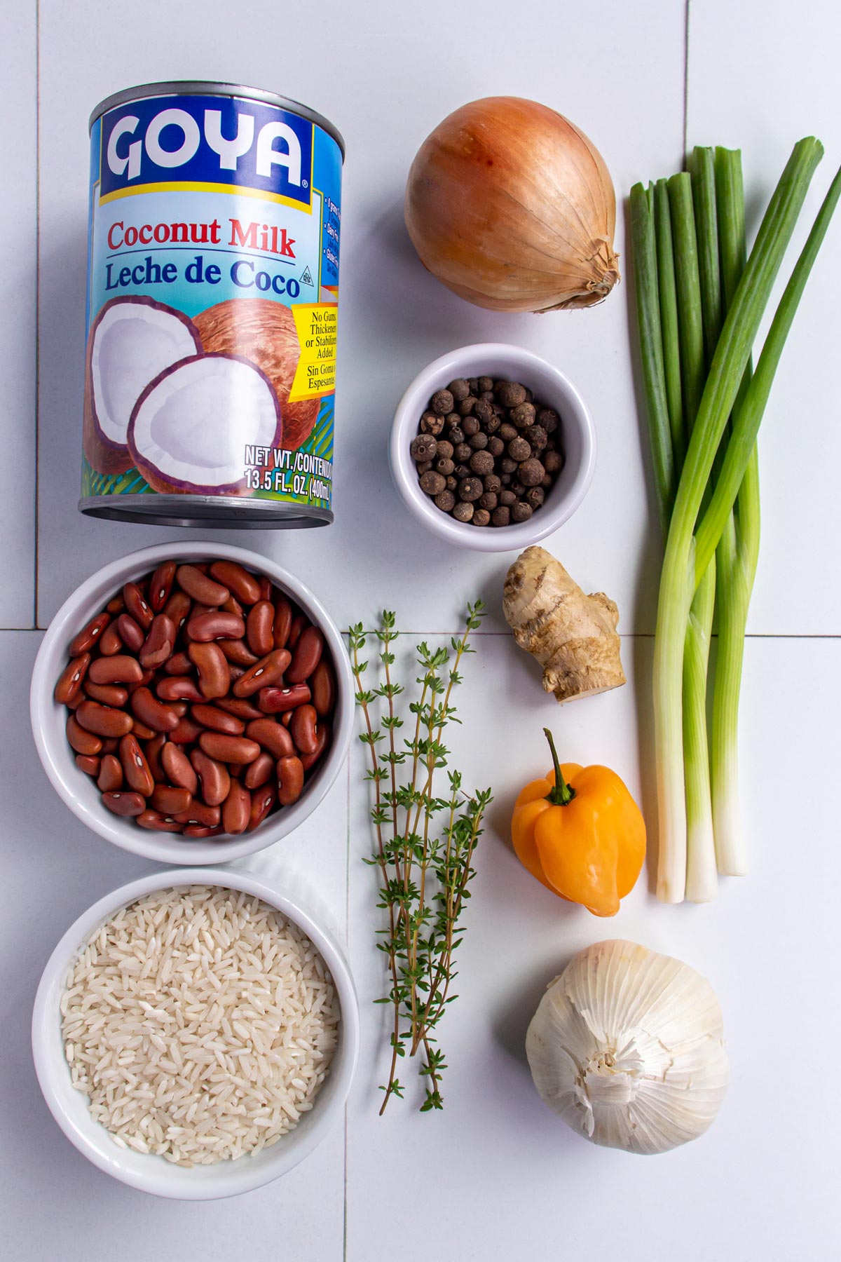 Ingredients for Jamaican rice and peas on a white tile background.