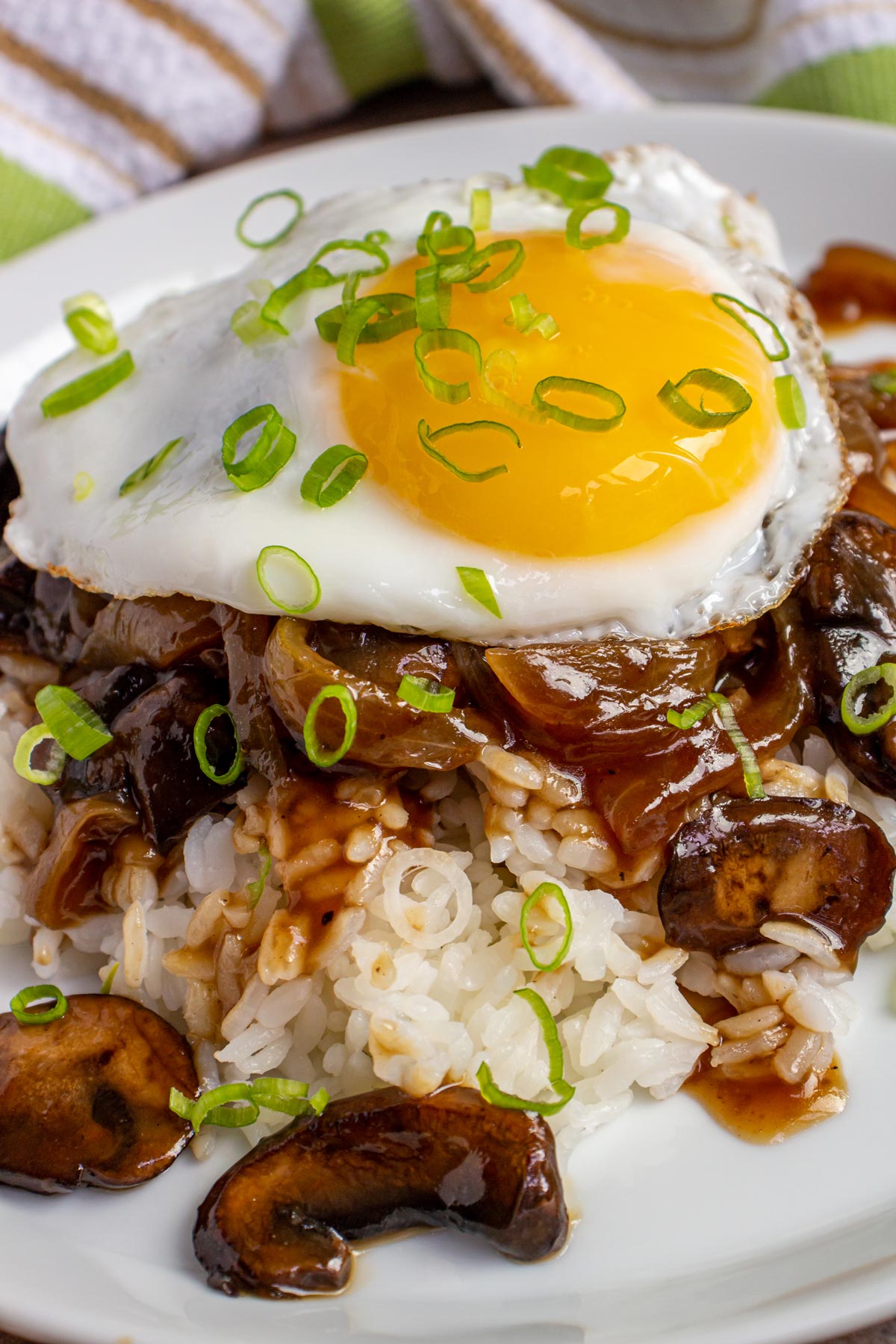 Closeup of a Hawaiian loco moco with brown gravy and fried egg on a white plate.