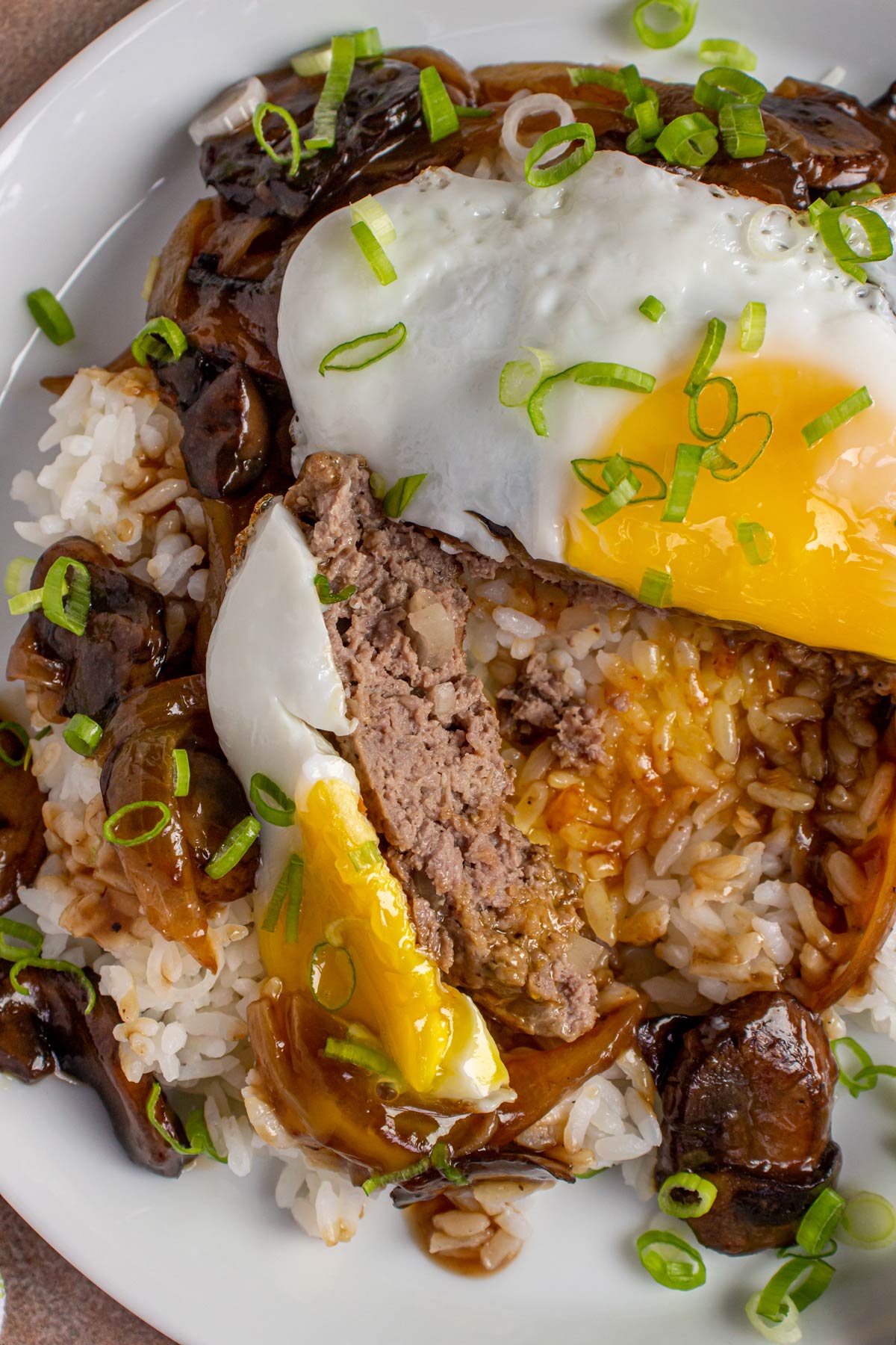 Closeup of a loco moco cut to show the burger patty beneath the fried egg.