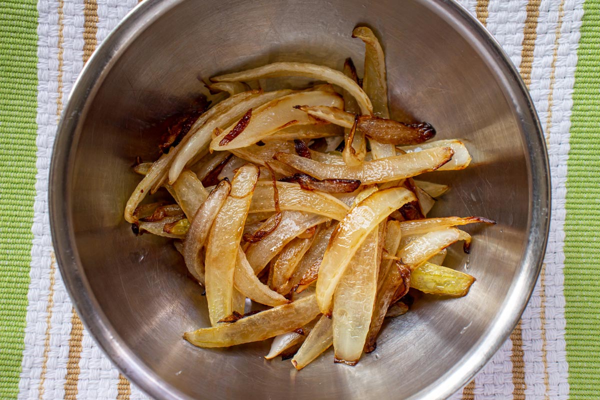 Cooked caramelized strips of onion in a small metal bowl.