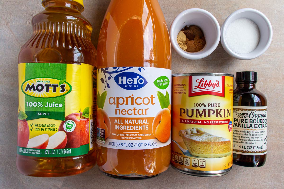 Bottles of apple juice and apricot nectar, a can of pumpkin, bottle of vanilla, and spices.