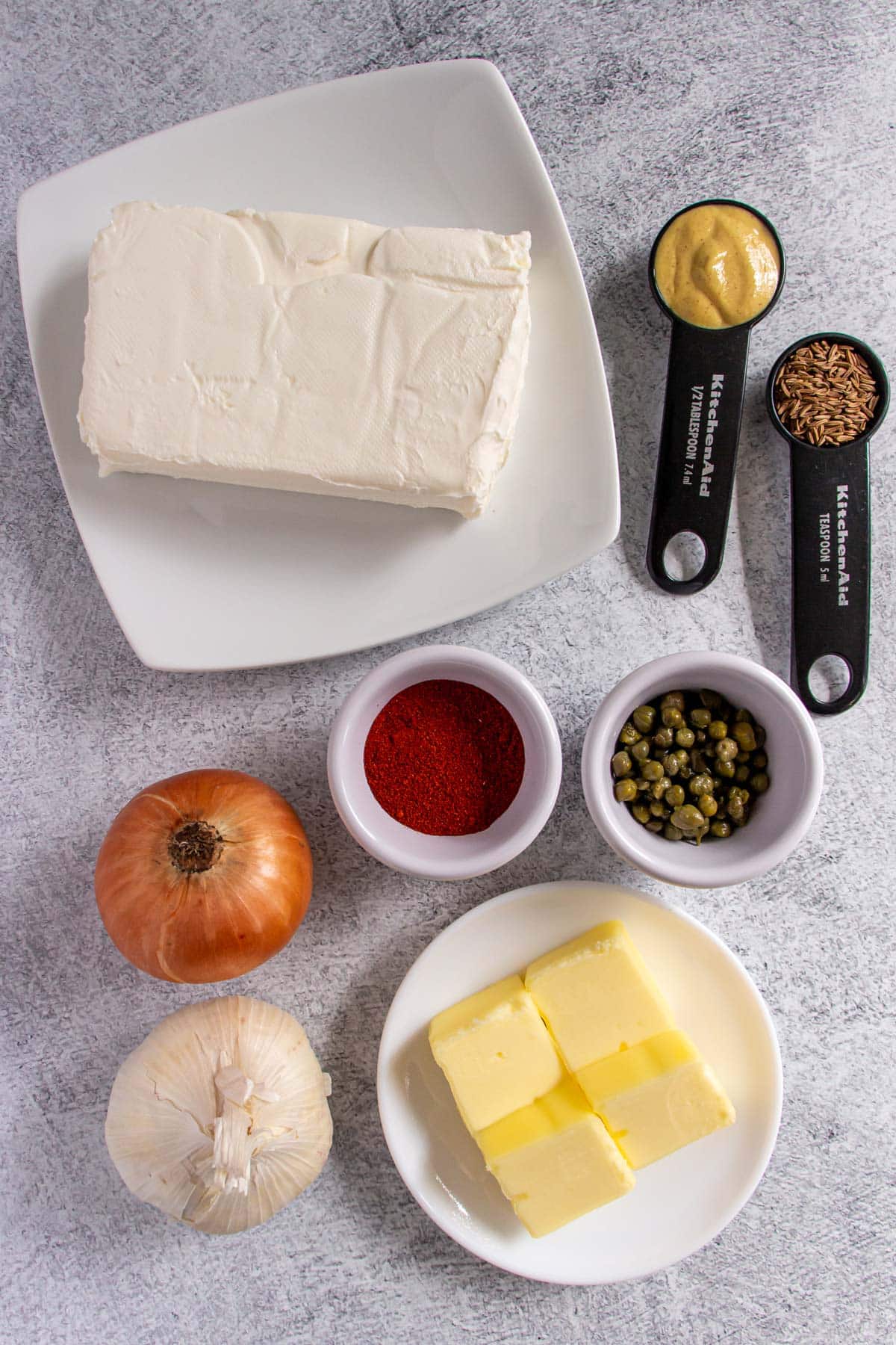 Ingredients for Liptauer cheese spread on a grey background.