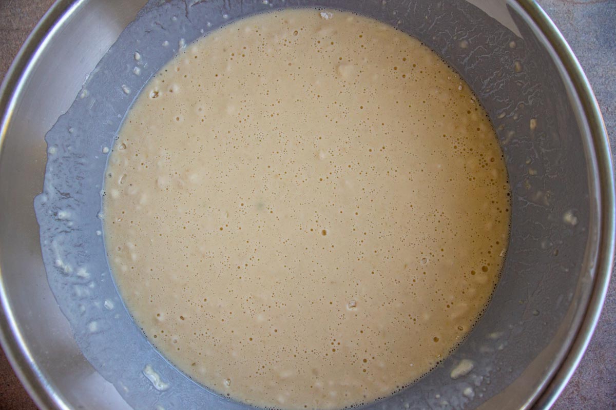 Thin pancake batter in a metal mixing bowl.