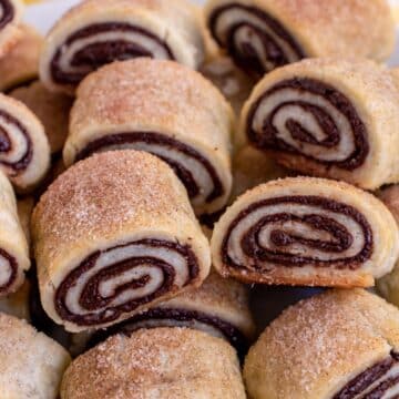A pile of chocolate rugelach pastries with a pinwheel pattern and cinnamon sugar on top.