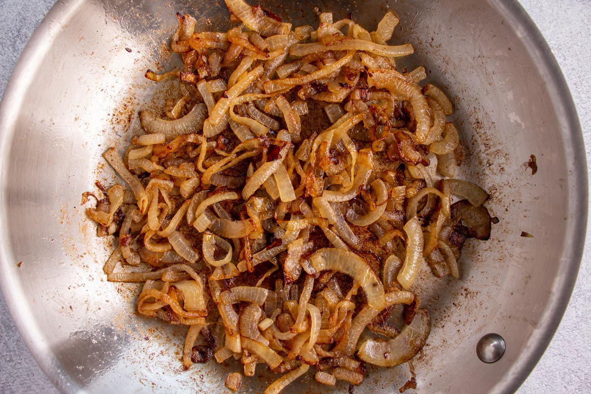 Dark brown fried onions in a stainless steel skillet.