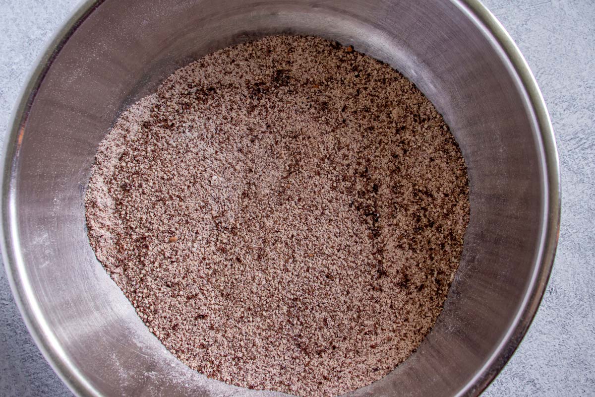 A mixture of dry ingredients included grated chocolate in a metal mixing bowl.