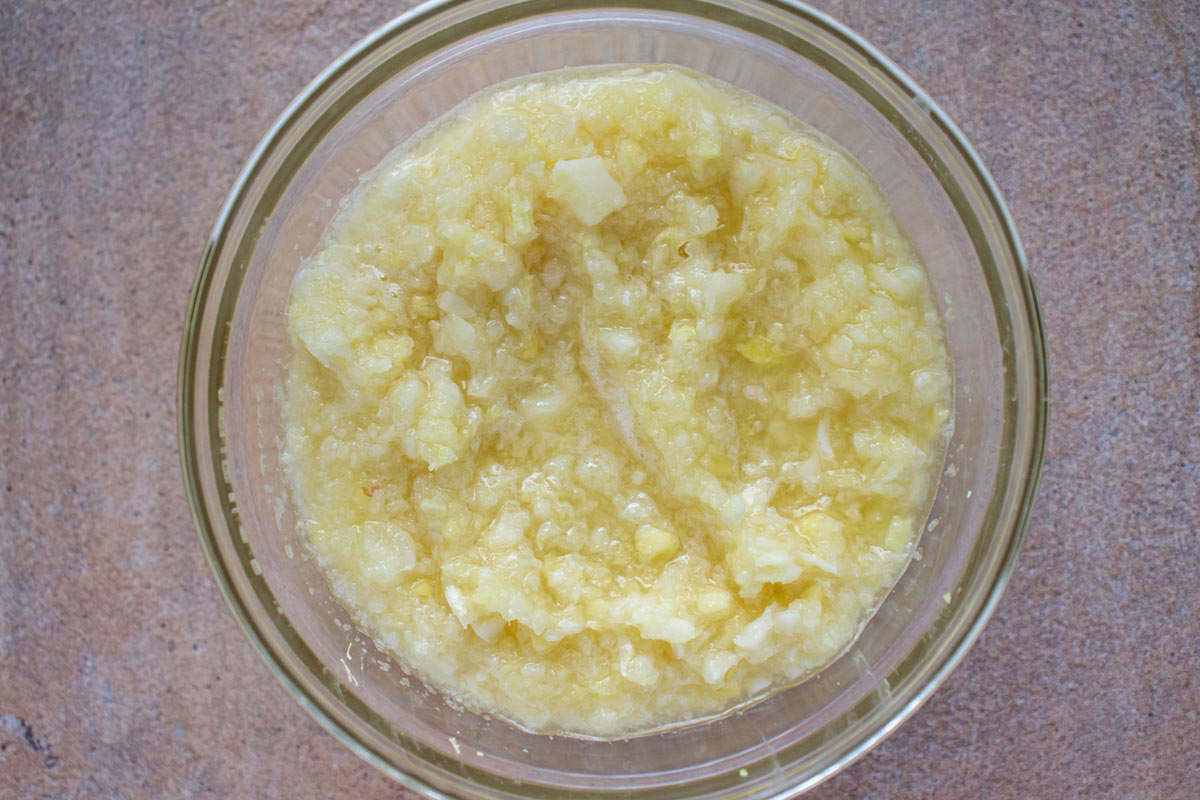 A yellowish ginger and garlic paste in a small glass bowl.