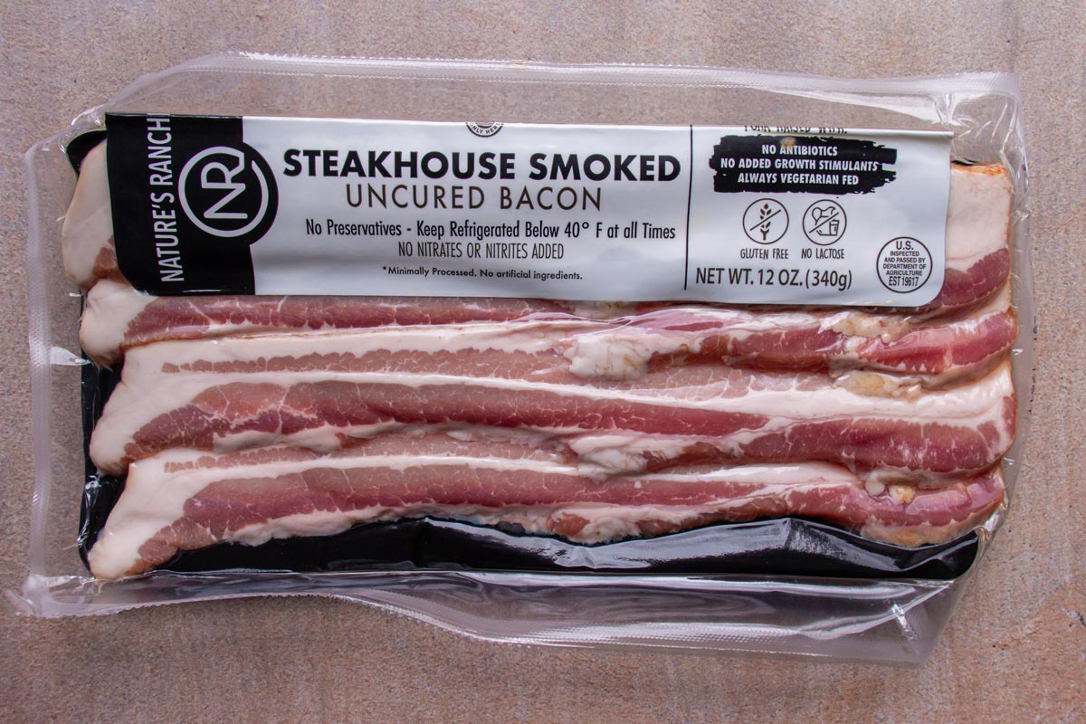 A package of thick-cut bacon on a beige background.