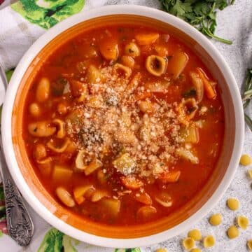 Closeup of a bowl of Italian minestrone soup topped with grated cheese.