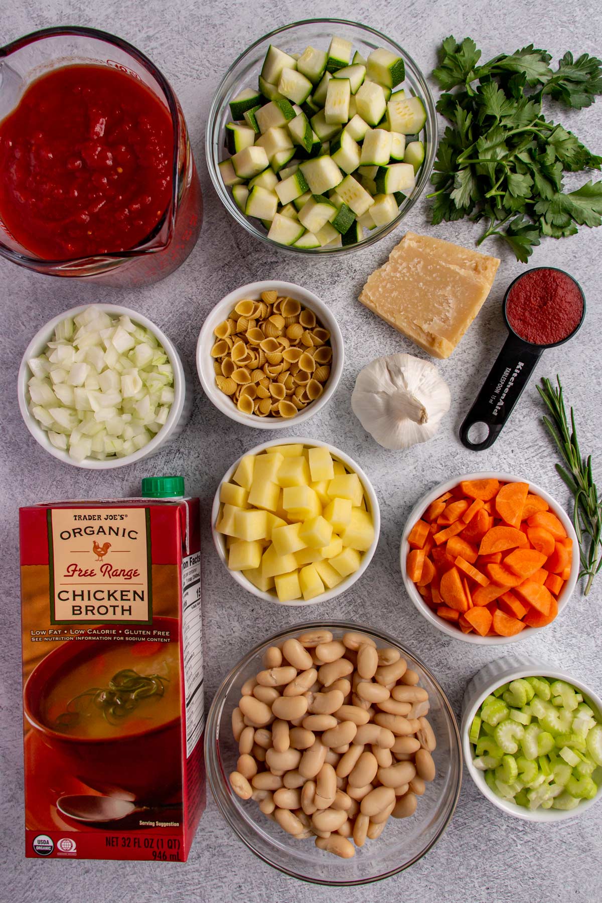 Ingredients for Italian minestrone soup on a light grey background.