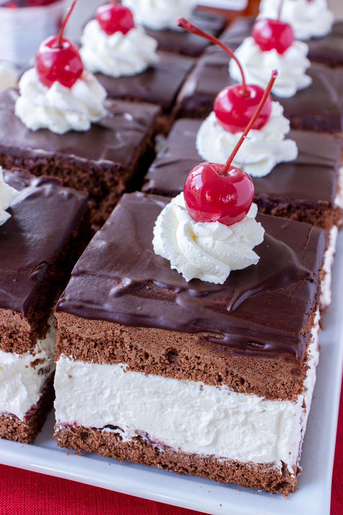 Two rows of square chocolate cake pieces filled with thick whipped cream on a white platter.