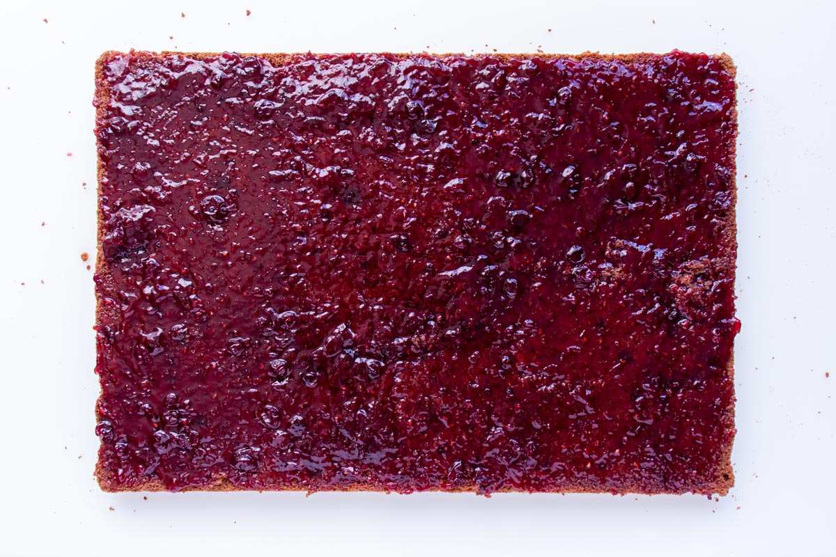 A rectangular cake spread from end to end with reddish jam.