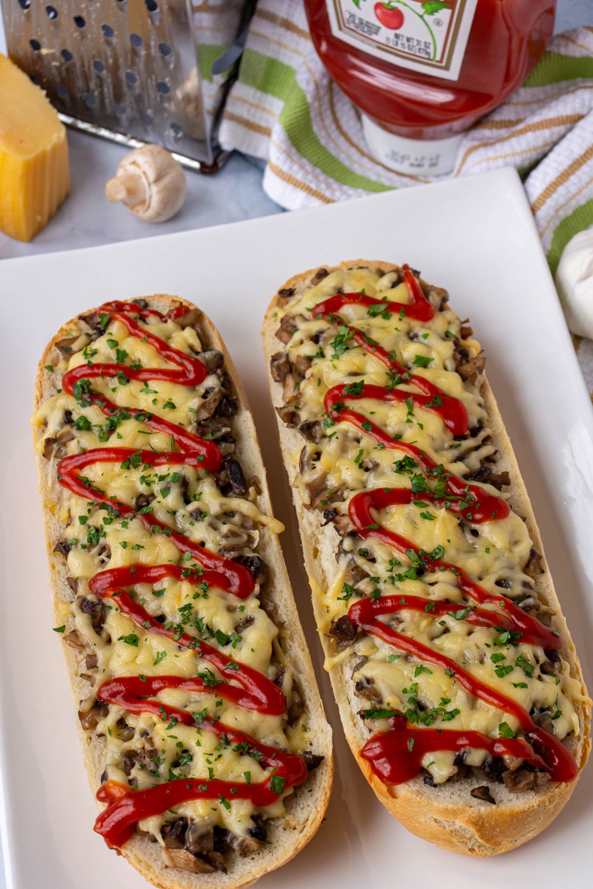 Two French bread Polish pizzas drizzled with ketchup on a white rectangular plate.