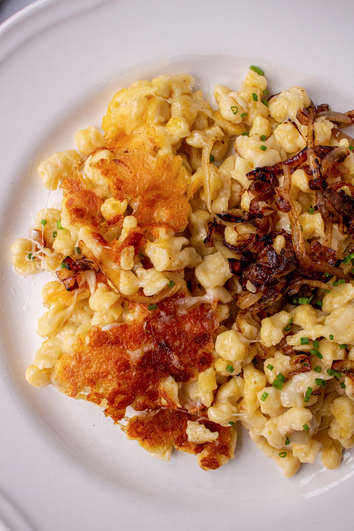 Closeup of a plate of kasnocken cheesy spaetzle showing off the crispy browned bottom crust.