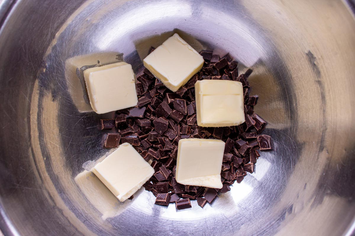 Pieces of butter and chopped chocolate in a metal bowl.