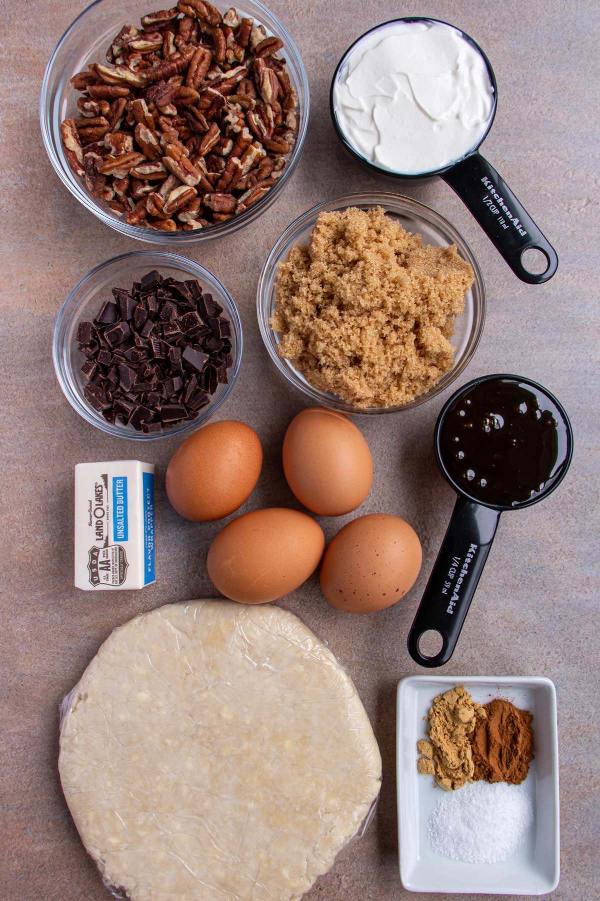 Ingredients for malted chocolate pecan pie on a beige background.