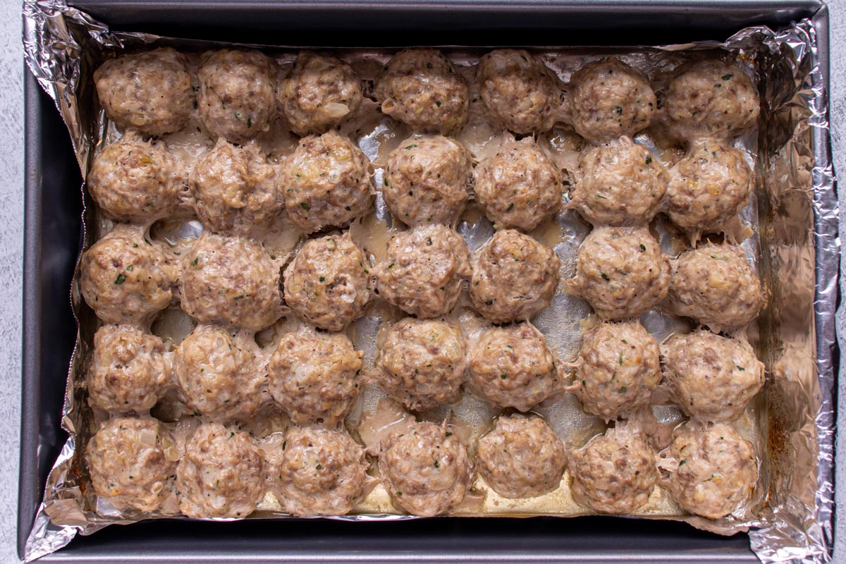 Meatballs baked in a foil-lined rectangular pan.
