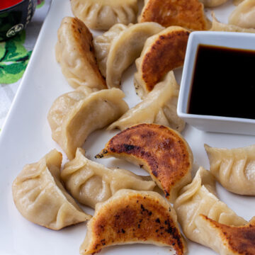 A platter of pan-fried Chinese dumplings with some upside down to show their crispy bottoms.