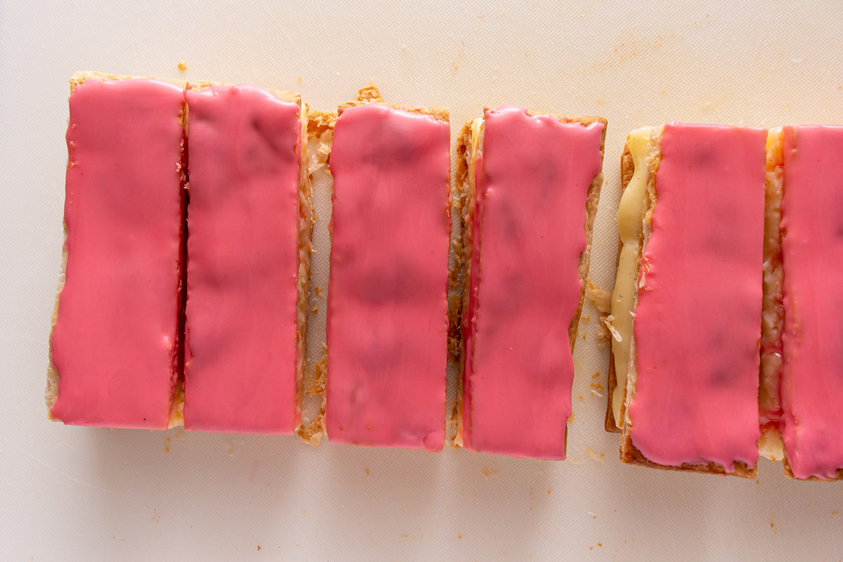 Rectangular pastries topped with pink glaze on a white board.