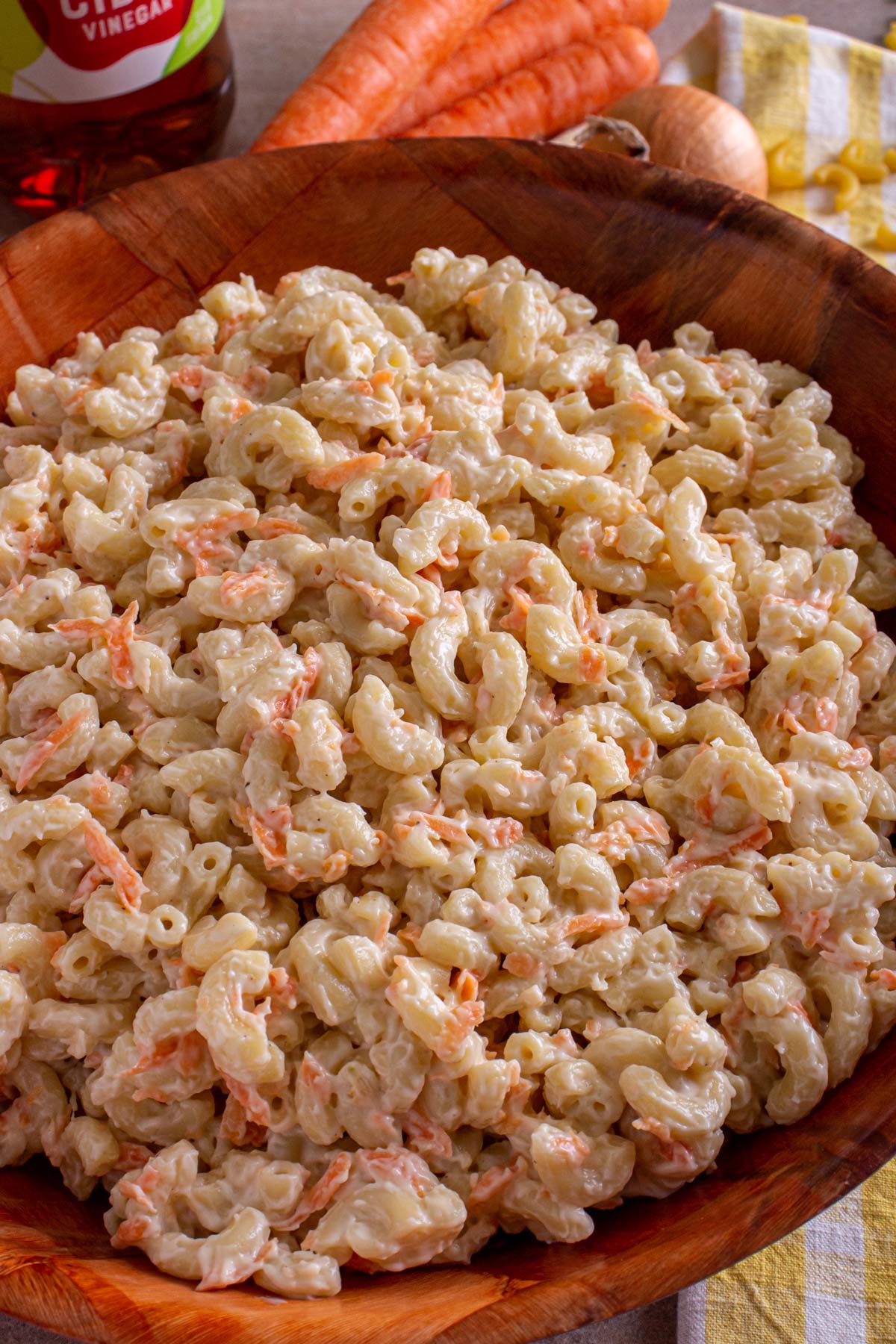 Hawaiian mac salad with grated carrots and mayo in a large wooden serving bowl.