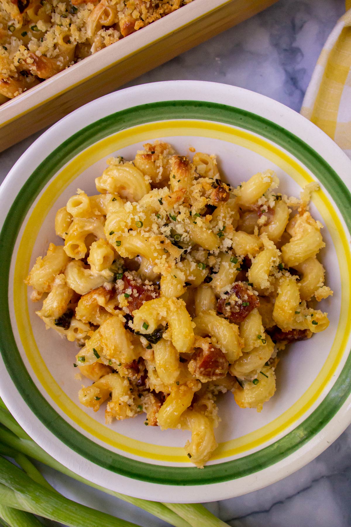 Chorizo and poblano mac and cheese in a green and yellow striped bowl.