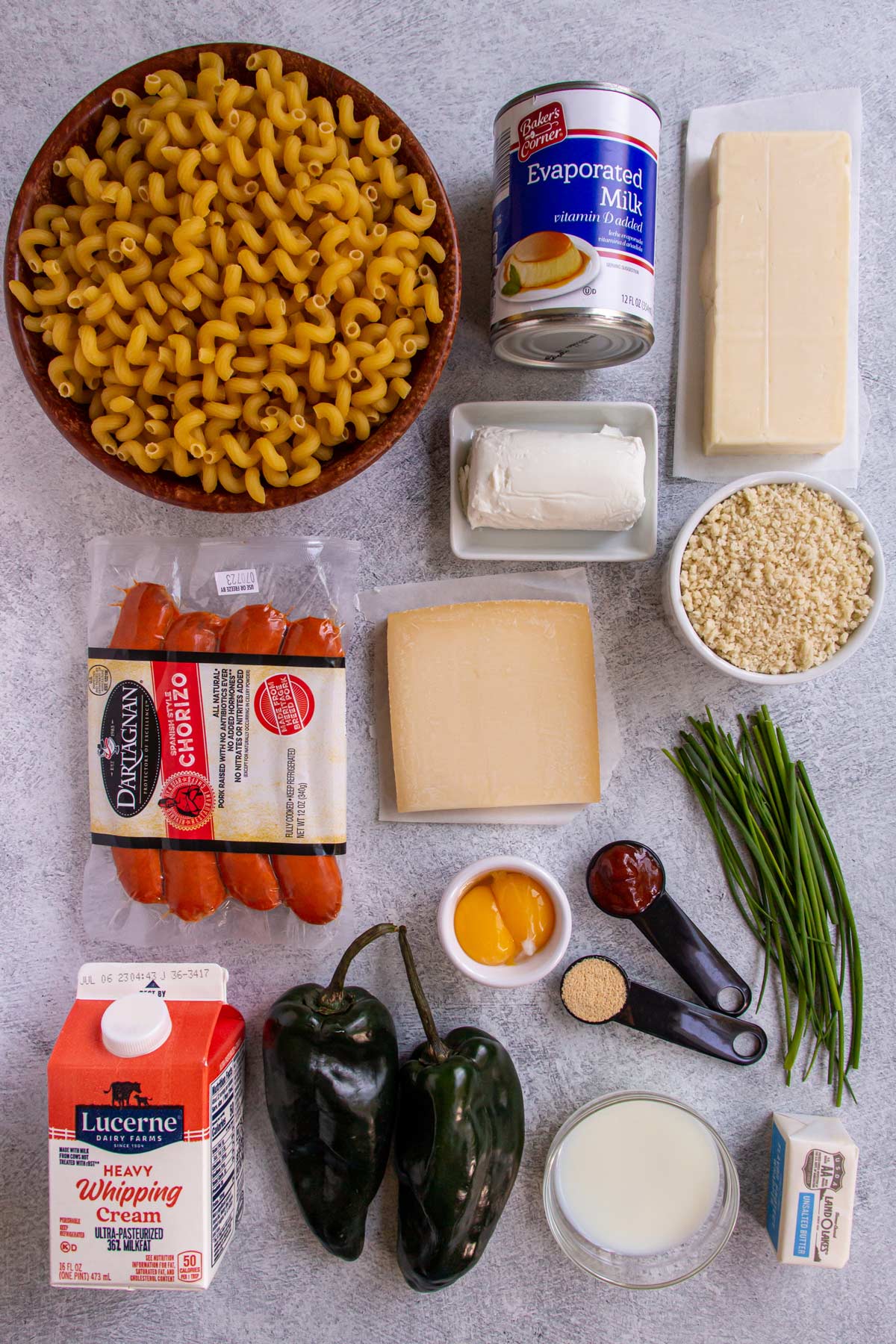 Ingredients for chorizo mac and cheese with poblanos on a light grey background.