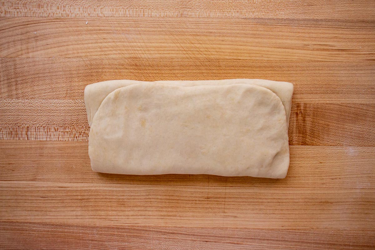 A rectangle of folded dough rotated 90 degrees so the long edge is facing you.