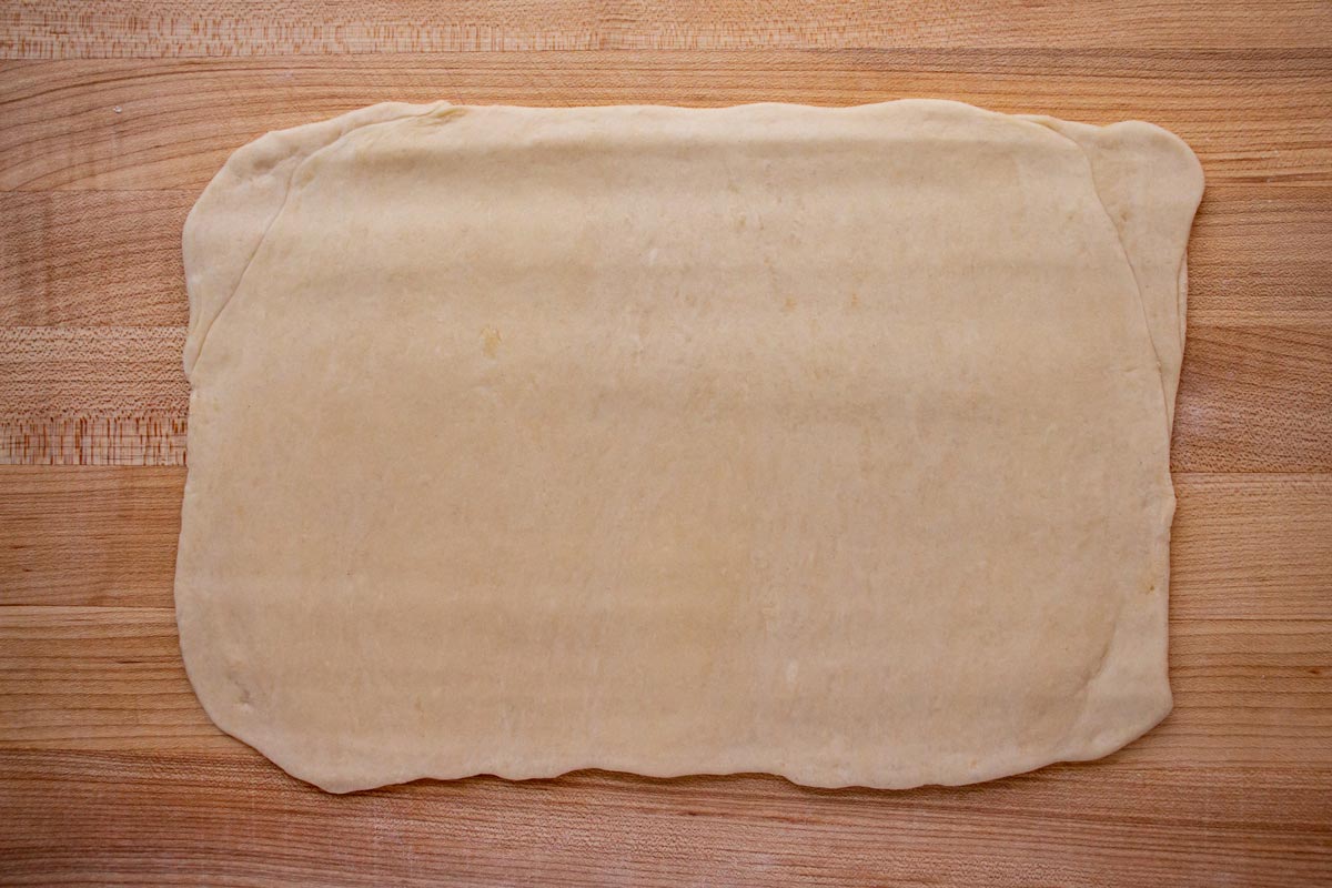 A rolled out rectangle of dough on a wooden board.