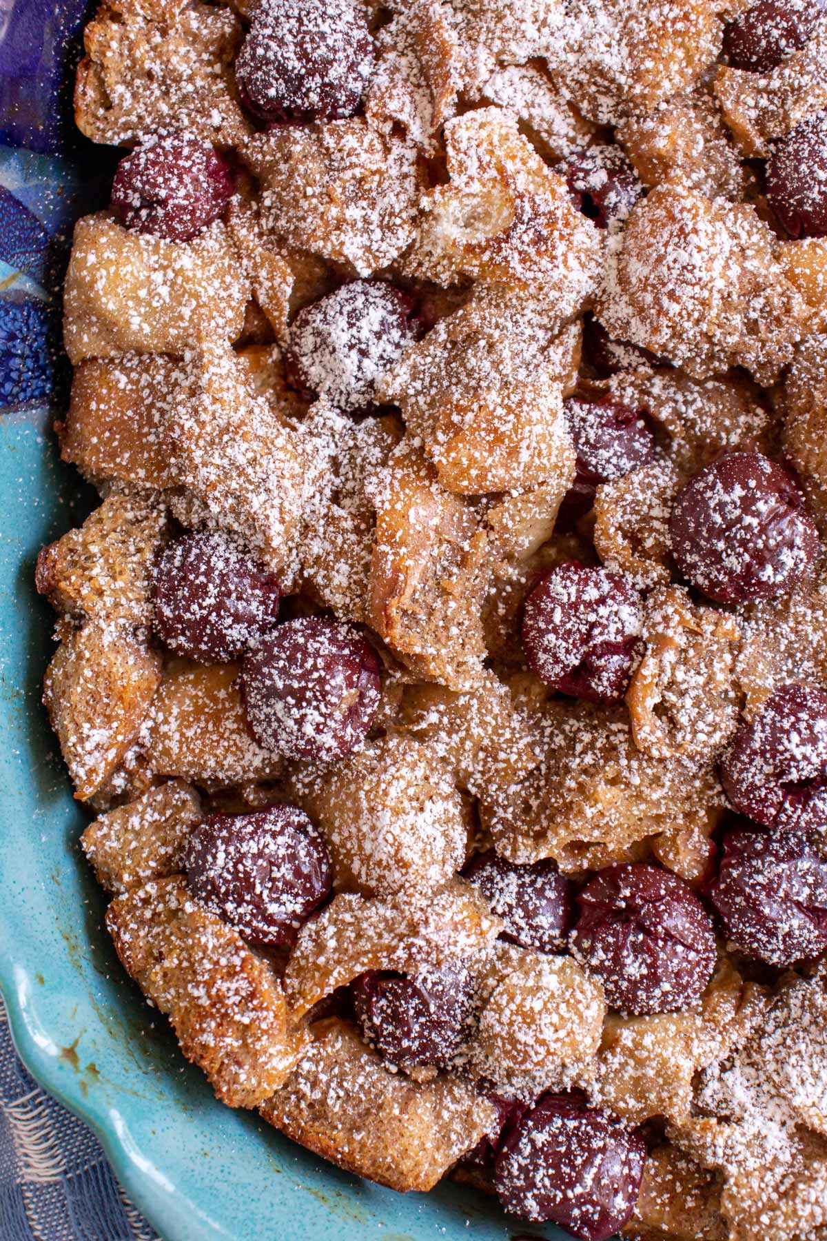 A closeup of kirschenmichel bread pudding with cherries topped with powdered sugar.