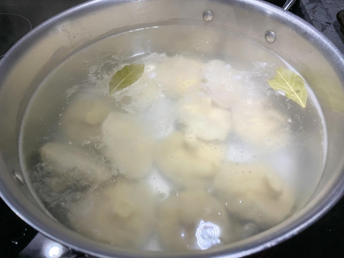 Georgian dumplings in a pot of simmering water with bay leaves.