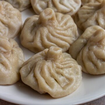 Closeup of khinkali dumplings on a white platter.