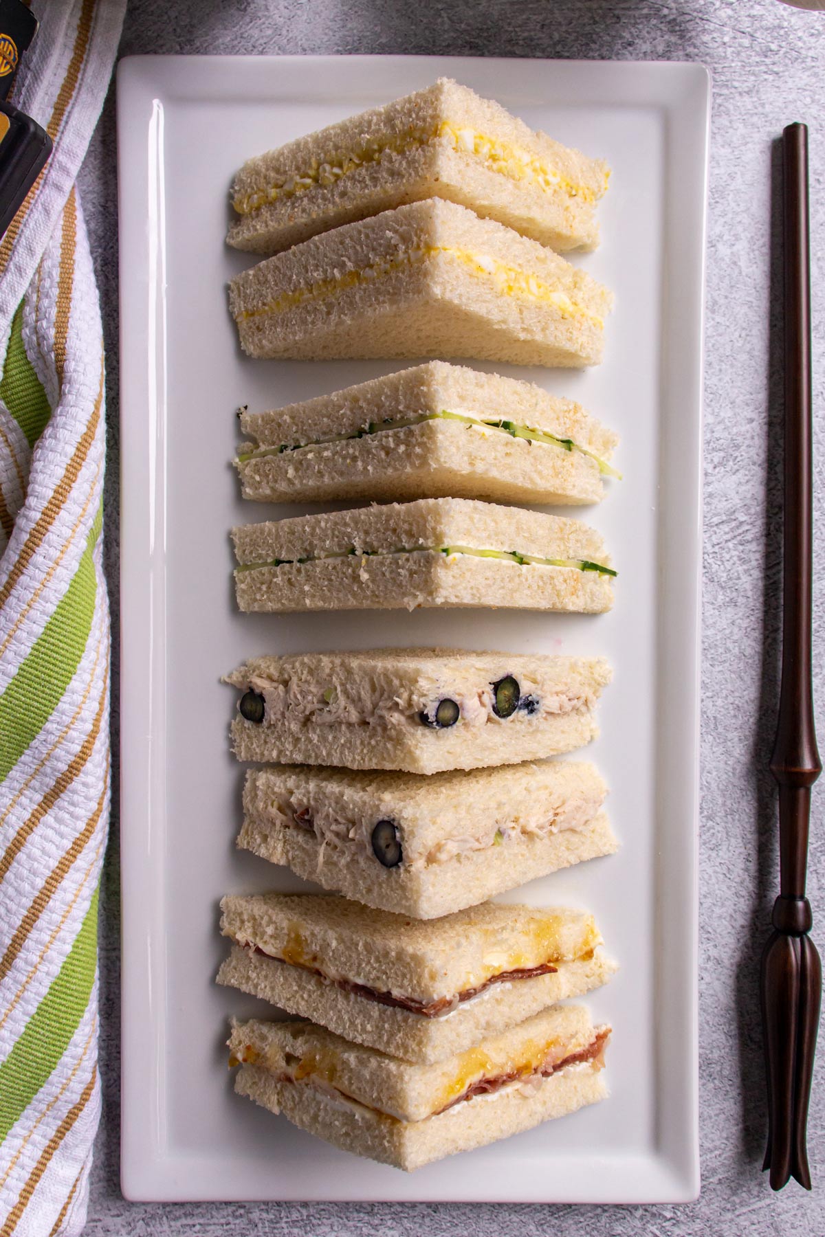 Harry Potter inspired afternoon tea sandwiches cut into triangles and arranged on a one rectangular platter.