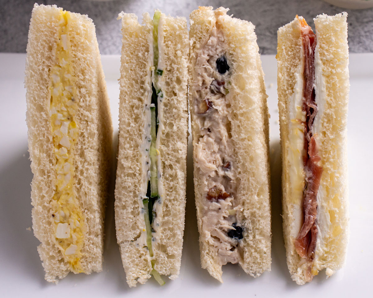 Closeup of 4 Harry Potter inspired tea sandwiches showing off their colorful fillings.