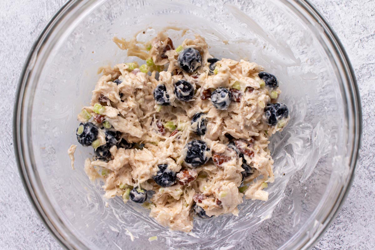 Chicken and blueberry salad with pecans in a glass bowl.