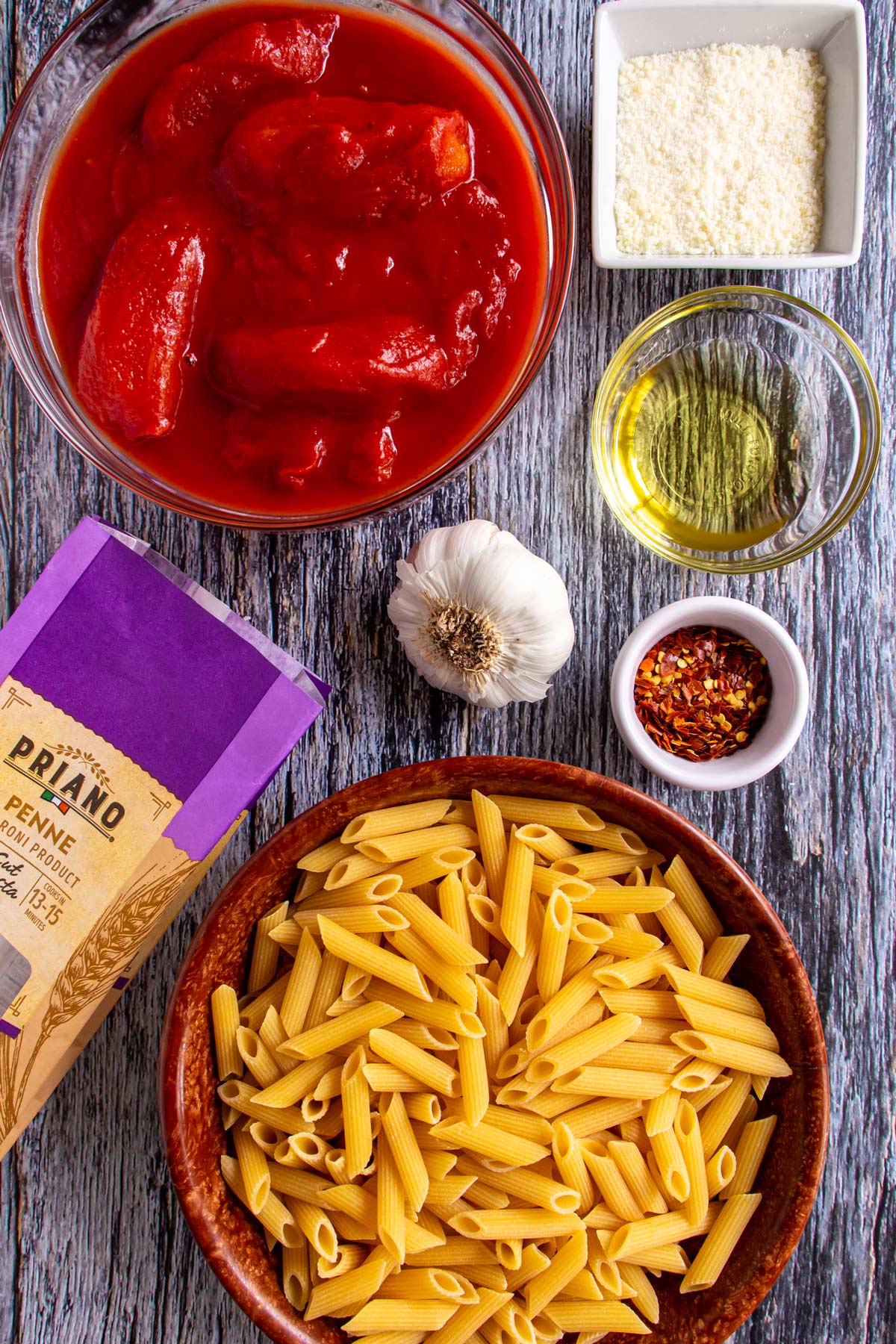 Ingredients for penne all' arrabbiata on a blue-grey wooden background.
