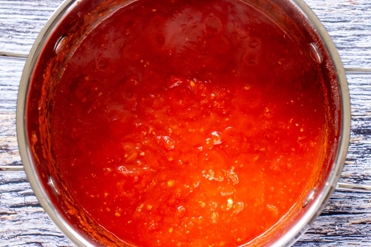 Crushed tomatoes in a metal pot after simmering.