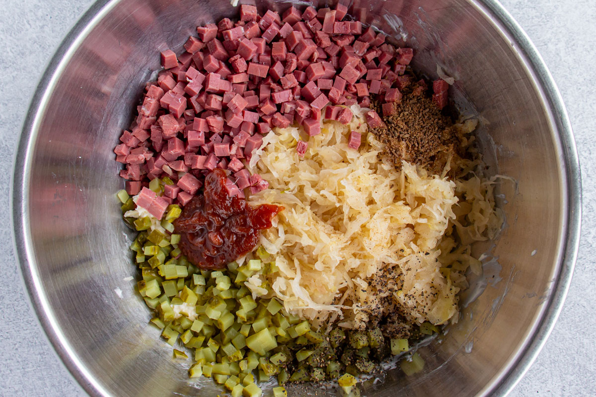 Various ingredients for Reuben dip in a metal bowl before mixing together.
