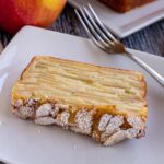A slice of invisible apple cake topped with sliced almonds and powdered sugar.