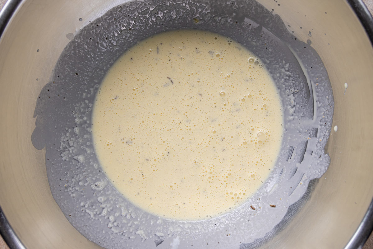 Eggs, cream, and seasonings in a metal mixing bowl after whisking.