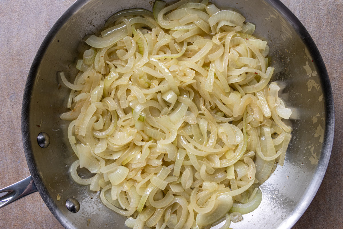 Sliced onions after cooking in a stainless steel skillet.