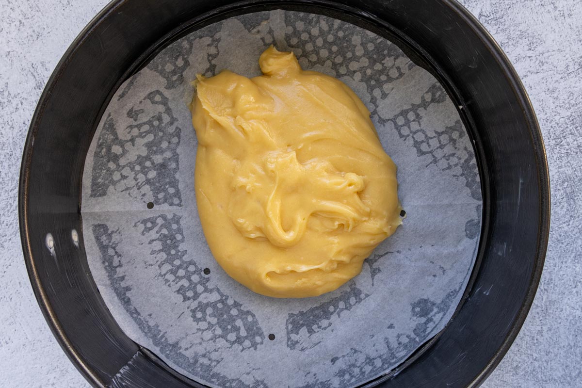 Choux dough in the center of a parchment paper lined springform pan.