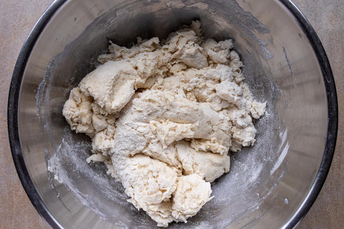 Dough for making buttermilk dumplings in a metal bowl.